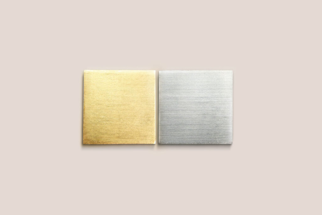 Zwei quadratische Edelmetallplatten in Gelbgold und Silber nebeneinander auf hellem Hintergrund – das Key Visual des neuen Markenauftritts von Burger Edelmetalle. Die Platten symbolisieren das Kerngeschäft der Scheideanstalt mit Edelmetallen wie Gold und Silber.