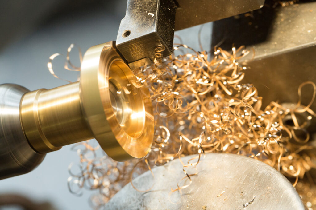 Hauseigene Ringfertigung bei Burger Edelmetalle: Eine CNC-Drehmaschine zerspant ein Metallrohr für die Produktion von Ringrohlingen, dabei entstehen spiralförmige Metallspäne. Burger produziert Ringrohlinge und Trauringe in der eigenen Fertigung in Keltern.