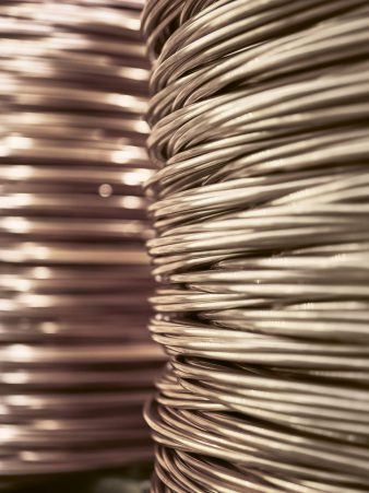 Nahaufnahme von Edelmetall-Drahtwicklungen auf großen Spulen bei Burger Edelmetalle, metallisch glänzend und engmaschig gewickelt. Edelmetall-Drähte aus Gold, Silber, Platin und Palladium gehören zum Halbzeug-Sortiment.