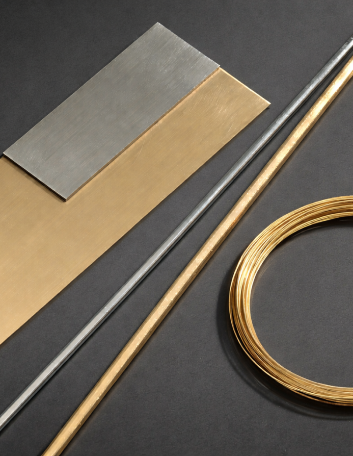 Edelmetall-Halbzeug-Sortiment von Burger mit Blechen, Stäben und Drahtwicklungen in Gold und Silber auf dunklem Untergrund. Das breite Halbzeug-Angebot umfasst verschiedene Legierungen und Formen für Werkstatt und Handel.