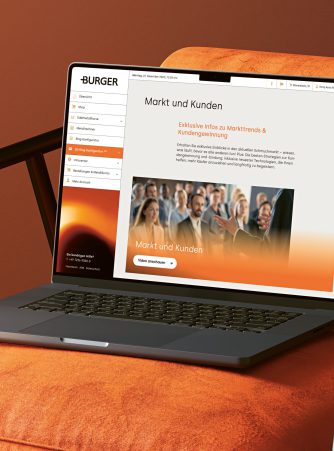 Ein Laptop auf einem orangefarbenen Stuhl zeigt auf der Seite "Markt und Kunden" eine deutsche Website mit Menüpunkten und einem Veranstaltungsfoto, das den Bereich Gekrätz Edelmetall zeigt.