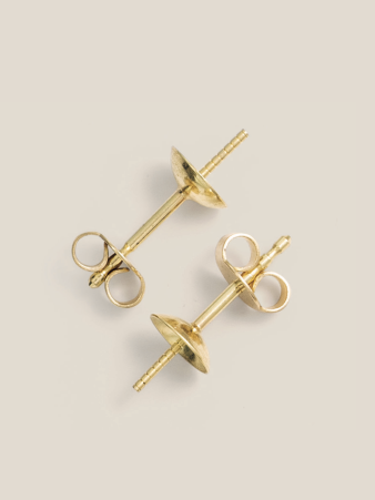 Goldene Ohrstecker-Furnituren von Burger Edelmetalle mit Schmetterlingsverschluss auf hellem Hintergrund. Die Edelmetall-Komponenten für die Schmuckfertigung sind in verschiedenen Legierungen erhältlich.